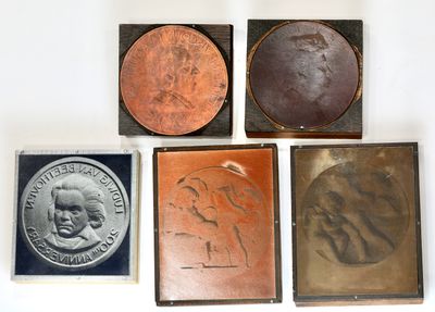 four different types of bronze and copper plaques on a white surface