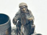 a figurine of a man sitting on a rock next to a cup