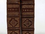 two old books sitting on top of each other on a white surface