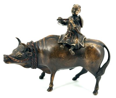 bronze figurine of a boy riding a bull with a bird on its back
