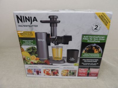 packaging of a juicer with a glass of juice in front of it