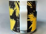 a yellow and black coffee cup with a white handle