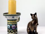 une statue de chat à côté d'un bougeoir avec une bougie