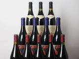 six bouteilles de vin sont posées sur une table devant un mur blanc