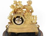 a gold clock on a black stand with a clock in the middle of it