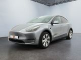 une Tesla Model Y argentée garée dans une pièce blanche