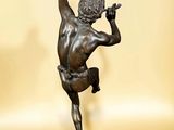 bronze statue of a boy with a flute on a marble base