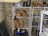 a small room with a table and shelves with pots and pans on it