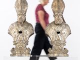 a woman walking past two statues of popes