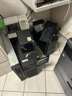 une pile d'ordinateurs et une imprimante posés par terre