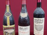 four bottles of wine are lined up on a red surface