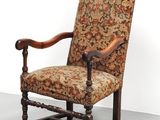 une vieille chaise avec un dossier et des accoudoirs tapissés de fleurs