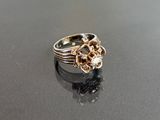 silver and gold ring with a flower design on a black surface