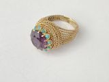a close up of a gold ring with a purple stone