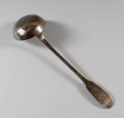 une cuillère ancienne avec un manche en métal posée sur une surface blanche