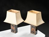 pair of black and gold lamps on a white pedestal against a black background