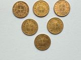 six different types of gold coins sitting on top of a white surface