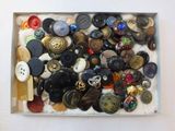 a box full of assorted buttons on a white surface
