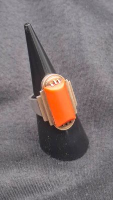a ring with an orange stone in it on a black cone