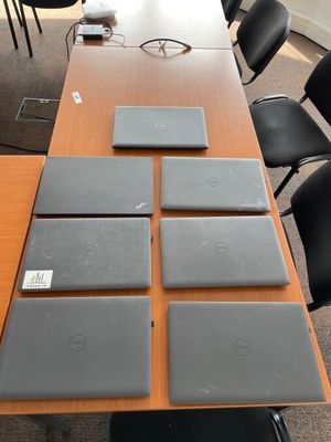 quatre ordinateurs portables posés sur une table dans une salle de réunion