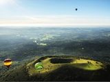 de nombreuses montgolfières survolant une colline verdoyante