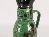 un vase vert avec une anse noire sur fond blanc