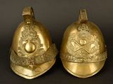 pair of antique brass fire helmets on a black background