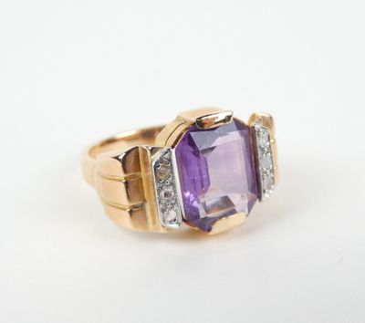 un gros plan d'une bague en améthore et diamant posée sur une surface blanche