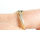 a woman ' s hand holding a gold ring with a diamond and a sapphire