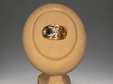 a gold ring with a diamond in it on a stand