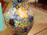 un vase coloré posé sur une table, sur laquelle se trouve une lampe