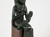 statue of a man sitting on a wooden block with a hat on his head
