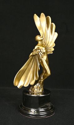 statue en or représentant une femme ailée, posée sur un socle noir