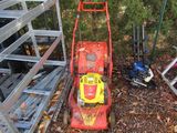 a red and yellow lawn mower sitting on the ground