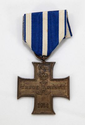une vieille médaille ornée d'une croix, posée sur une table blanche