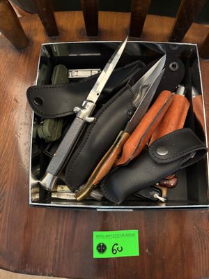une boîte remplie de couteaux de toutes sortes posée sur une chaise