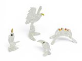trois figurines blanches représentant des oiseaux et un oiseau perché sur une branche