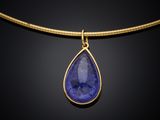 a gold necklace with a blue tear shaped stone on a gold chain