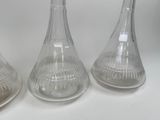 three clear glass vases sitting next to each other on a white surface