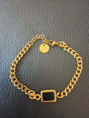 a gold bracelet with a black stone on it