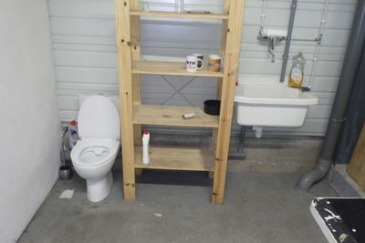une salle de bains équipée de toilettes, d'un lavabo et d'une étagère