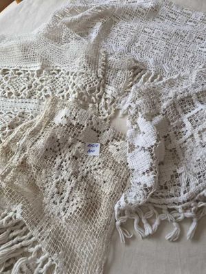 un châle blanc au crochet posé sur un lit