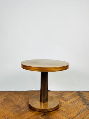 une table ronde en bois avec un piètement en métal, posée sur un parquet