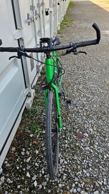 a green bike that is parked next to a building