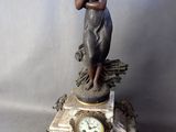 une statue de femme tenant une horloge sur une table