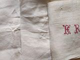 three pieces of cloth with red embroidery on them sitting on top of a table