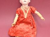 an image of a doll is sitting on a pink surface
