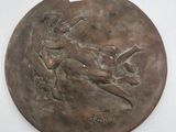 une image représentant une plaque en bronze sur laquelle figure un oiseau, sur le dos