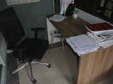 a desk with a computer and a chair in a room