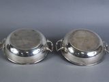 two silverplated dishes with handles and handles on a gray surface